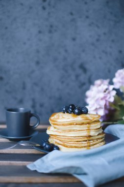 Krepler, üzerinde bir fincan kahve olan ahşap masa, gri bir arka plan..