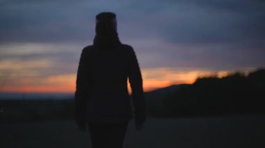 Bir kadın gün batımında uzaklaşırken odaklanamaz..