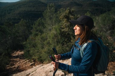 Şapkalı ve sırıklı bir kadın sabah güneşinin tadını çıkarıyor..