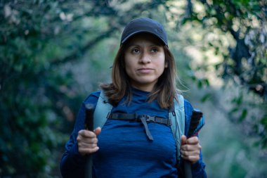 Yürüyüş direkleri olan kadın, yürüdüğü dağ yolunu gözlemliyor..