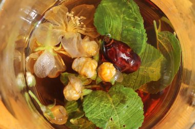 Gül kalçalı bitki çayı, elma çiçekleri ve cam kavanozda nane şekeri.