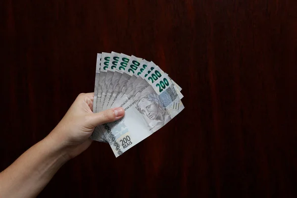 Hands holding Brazilian real notes, Brazil BRL banknote, Brazilian currency, economy and business.