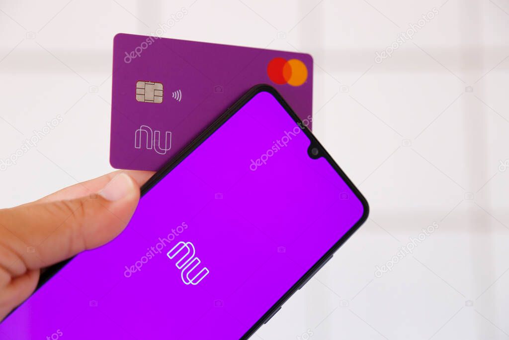 Minas Gerais, Brazil - January 25, 2021: mobile phone display and credit card with Nubank and Mastercard brand. Digital payment system.