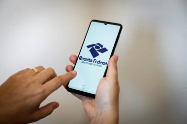 Minas Gerais, Brezilya - 21 Mart 2021: Müşteri Brezilya federal gelirinin gelir vergisi uygulamasını cep telefonunda kullandı