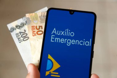 Minas Gerais, Brezilya - 6 Nisan 2021: Cep telefonu uygulaması ve para faturalarında Auxilio Emergencial
