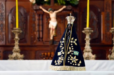 Arka planda seçici odak noktası ve İsa 'nın haçı olan Brezilya' nın koruyucu azizi Nossa Senhora Aparecida 'nın heykeliyle sunak.