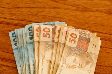 Brezilya 'da finans, ekonomi ve zenginlik temaları için mükemmel olan kırsal ahşap masaya yayılmış yüz elli gerçek banknot aç