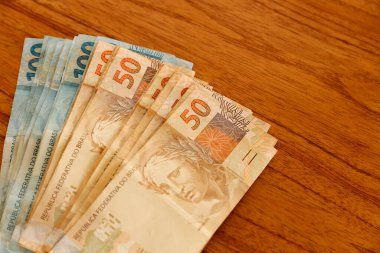 Brezilya 'da finans, ekonomi ve zenginlik temaları için mükemmel olan kırsal ahşap masaya yayılmış yüz elli gerçek banknot aç