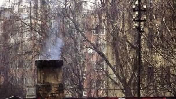 Rykande skorstenen och intensiva snöfall i staden — Stockvideo