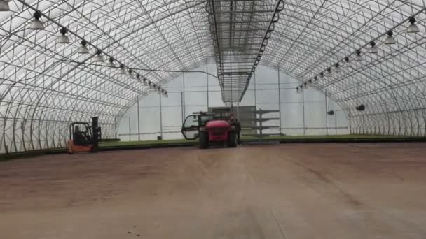 Two tractors - lifts working in a large glasshouse — Stock Video