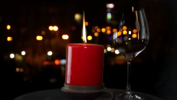 Rote Kerze und ein Glas Rotwein in der Nacht auf dem Hintergrund der Stadt — Stockvideo