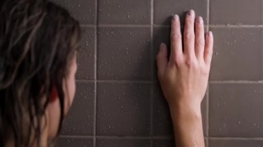 Çekici esmer, orta yaşlı kadın duş alıyor. Kadın saçını yıkıyor. Çıplak vücut. Duvarlarda gri fayans var. Cilt bakımı, rutin ev tedavileri.