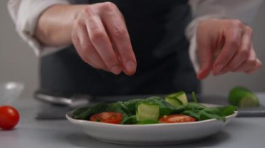 Kadın bir şef sebzeden bir salata yapar. Eller yemek servisi yapar..