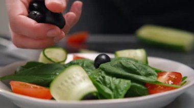 Kadın bir şef sebzeden bir salata yapar. Eller yemek servisi yapar..