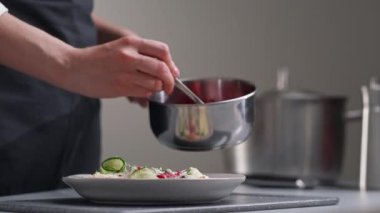 Beyaz üniformalı bir kadın şef ve restoran mutfağında siyah önlük. Aşçı kırmızı kızılcık salatası sosu döker. Yemek yapmak ve dekore etmek..