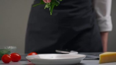 Salata yapıyorum. Yeşil ıspanak yaprakları yavaşça tabağa düşer. Restoranın mutfağında çalışan bir kadın şefin işi..