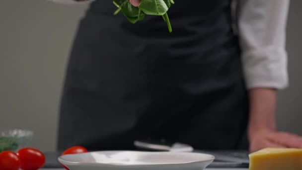 Gör en sallad. De gröna spenatbladen faller långsamt ner i tallriken. Arbete som kvinnlig kock i restaurangens kök. — Stockvideo