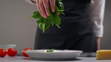 Salata yapıyorum. Yeşil ıspanak yaprakları yavaşça tabağa düşer. Restoranın mutfağında çalışan bir kadın şefin işi..