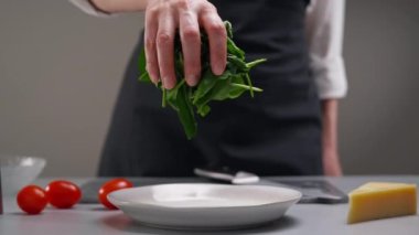 Salata yapıyorum. Yeşil ıspanak yaprakları yavaşça tabağa düşer. Restoranın mutfağında çalışan bir kadın şefin işi..