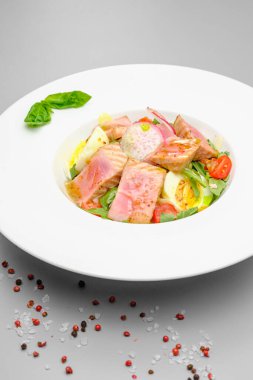 Yumurtalı ton balığı salatası, domates ve beyaz tabakta salata. Restoranda öğle yemeği..