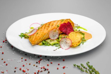 Beyaz tabakta sebzeli ızgara somon bifteği..