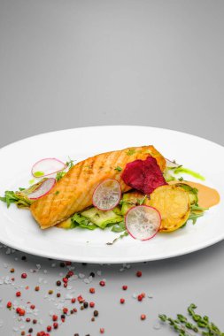 Beyaz tabakta sebzeli ızgara somon bifteği..