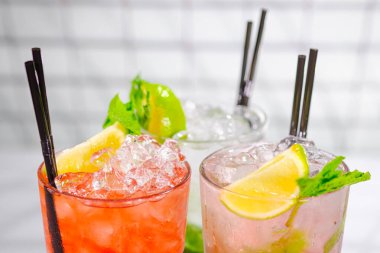Üç ferahlatıcı yaz kokteyli bardakta ve bar rafında tüpler..