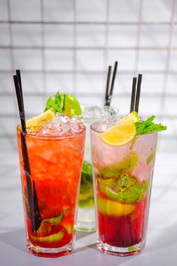 Üç ferahlatıcı yaz kokteyli bardakta ve bar rafında tüpler..
