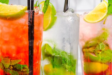 Üç ferahlatıcı yaz kokteyli bardakta ve bar rafında tüpler..