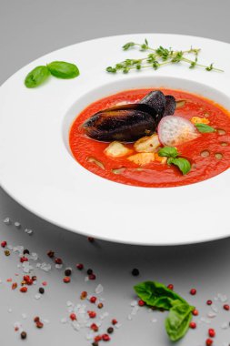 Domates çorbası. Gri arka planda beyaz bir tabakta deniz ürünleri midyesi püresi..