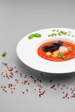Domates çorbası. Gri arka planda beyaz bir tabakta deniz ürünleri midyesi püresi..