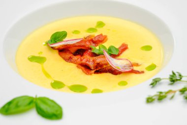 Fesleğenle süslenmiş füme etli mısır kremalı çorba, gri bir arka planda. Restoran menüsündeki ilk yemek..