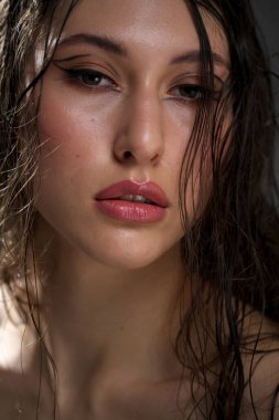 Yakından ıslak siyah saçlı güzel bir genç kızın yüzü. Doğu görünüşü. Çıplak makyaj, doğal ten..