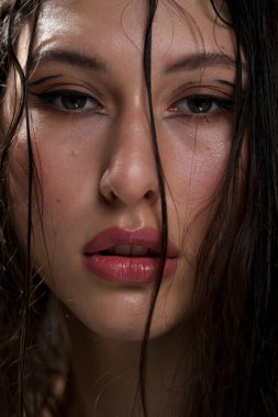 Yakından ıslak siyah saçlı güzel bir genç kızın yüzü. Doğu görünüşü. Çıplak makyaj, doğal ten..