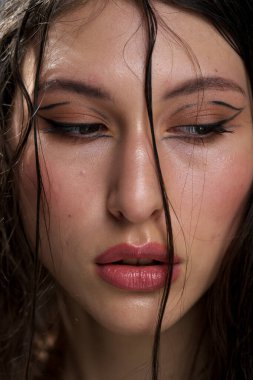 Yakından ıslak siyah saçlı güzel bir genç kızın yüzü. Doğu görünüşü. Çıplak makyaj, doğal ten..