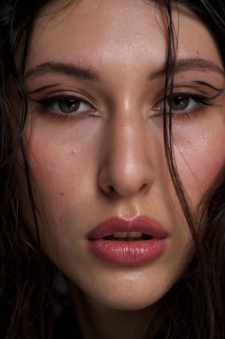 Yakından ıslak siyah saçlı güzel bir genç kızın yüzü. Doğu görünüşü. Çıplak makyaj, doğal ten..