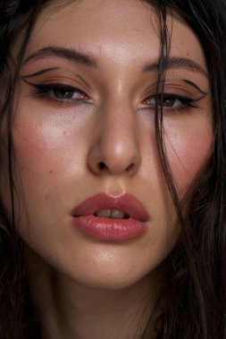 Yakından ıslak siyah saçlı güzel bir genç kızın yüzü. Doğu görünüşü. Çıplak makyaj, doğal ten..