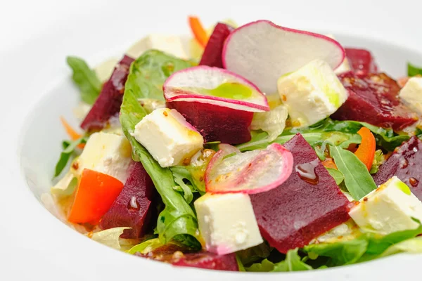 Овочевий салат з редькою, м'яким сиром, буряком і зеленню в білій тарілці на сірому фоні. Закуски в ресторані . — стокове фото