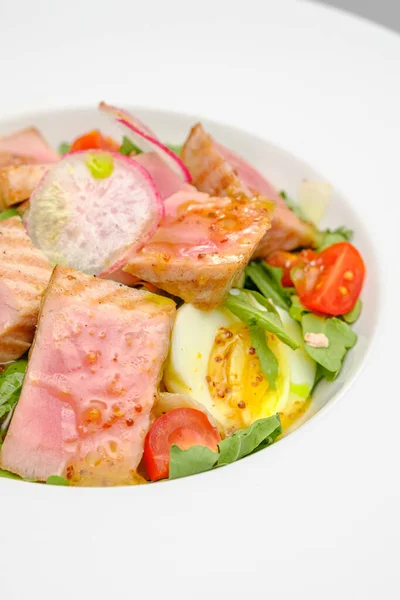 Салат з тунцем з яйцем, помідорами та салатом на білій тарілці. Обід у ресторані . — стокове фото