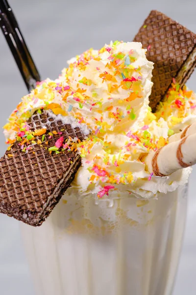 Witte milkshake met slagroomdecor en een buisje op de bar. — Stockfoto