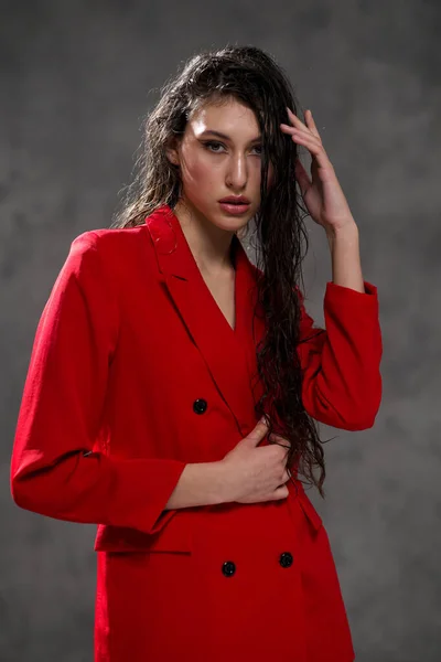 Una giovane bella donna orientale con lunghi capelli neri in una giacca rossa su uno sfondo nero. La modella posa in studio. — Foto Stock