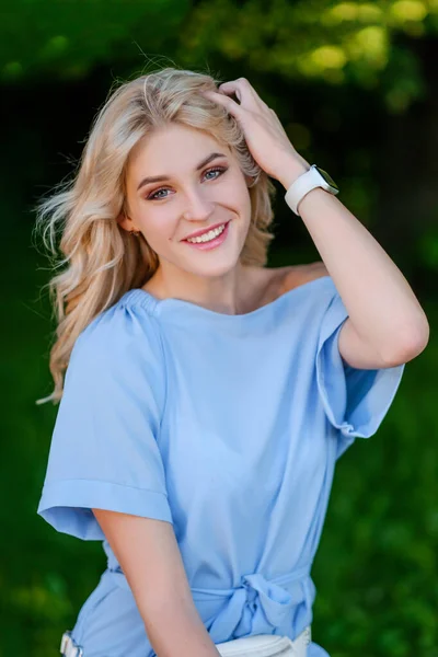 Ritratto di una giovane bella ragazza di 21 anni in un abito estivo blu con una borsa bianca. La donna sorride. Belle labbra e occhi. Capelli lunghi sciolti. — Foto Stock