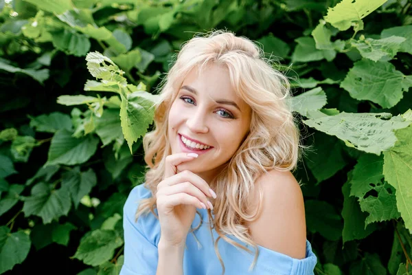 Retrato de uma menina bonita jovem 21 anos de idade em um vestido de verão azul com um saco de cinto branco. A mulher sorri. Lindos lábios e olhos. Cabelo longo e solto. Fotos De Bancos De Imagens