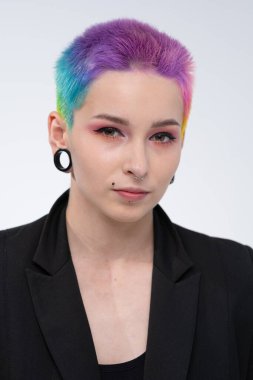 Kısa renkli saçlı güzel bir kız. Parlak renklendirme ve yaratıcı makyaj. Yüzünde piercing var. Siyah bir ceket..