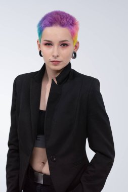 Kısa renkli saçlı güzel bir kız. Parlak renklendirme ve yaratıcı makyaj. Yüzünde piercing var. Siyah bir ceket..