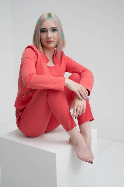 Portrait of a young beautiful informal blonde girl with dyed hair. Red jacket suit on the naked body. Studio photoshoot on a white background.