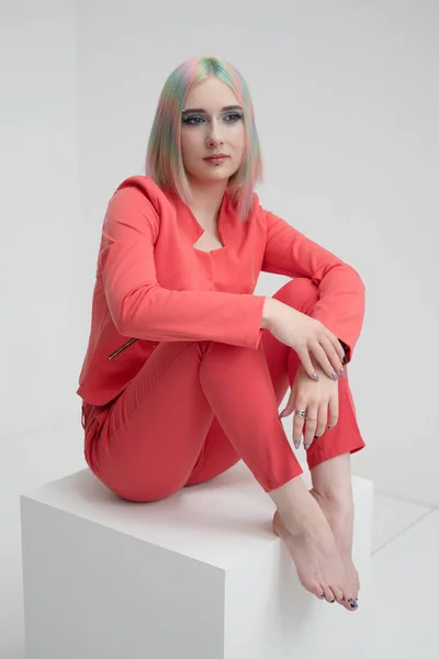 Portrait of a young beautiful informal blonde girl with dyed hair. Red jacket suit on the naked body. Studio photoshoot on a white background. — Stock Photo, Image