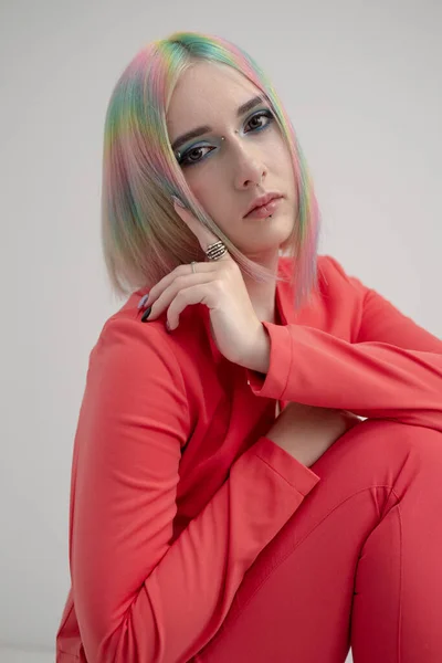 Portrait of a young beautiful informal blonde girl with dyed hair. Red jacket suit on the naked body. Studio photoshoot on a white background.