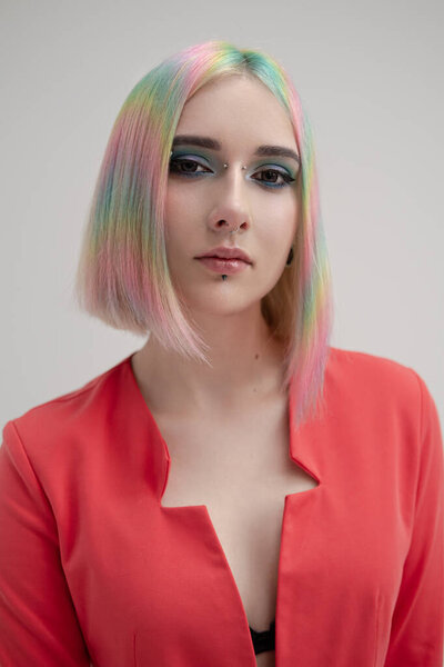 Portrait of a young beautiful informal blonde girl with dyed hair. Red jacket suit on the naked body. Studio photoshoot on a white background.