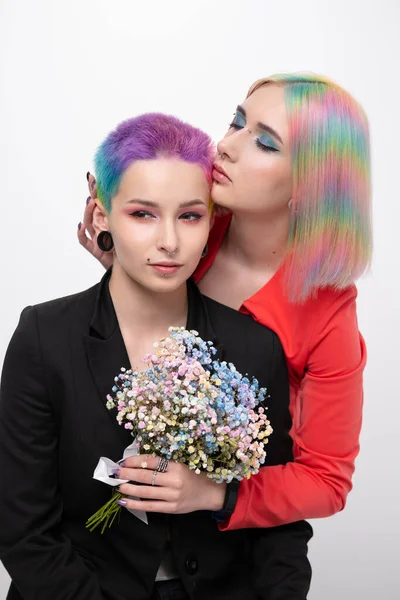 Young lesbian woman couple with vivd colored short hair and jackets posing on white background. Piercing on the face, tunnels in the ears. — Stock Photo, Image